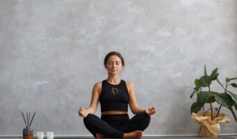 Portrait of sporty young woman doing exercises on yoga lesson at home. Beautiful girl practicing easy yoga pose, sukhasana. Yoga postures,meditation,relaxation,stress management, wellbeing and health