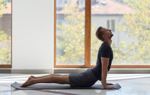 full-shot-man-practicing-cobra-pose-indoor