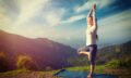 Woman in yoga asana Vrikshasana tree pose in mountains outdoors