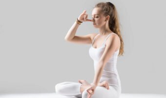 Young attractive woman making Alternate Nostril Breathing, grey